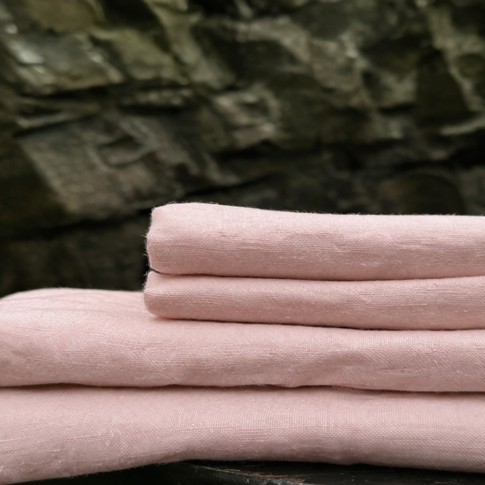 Stack of soft pink linen against a rock background