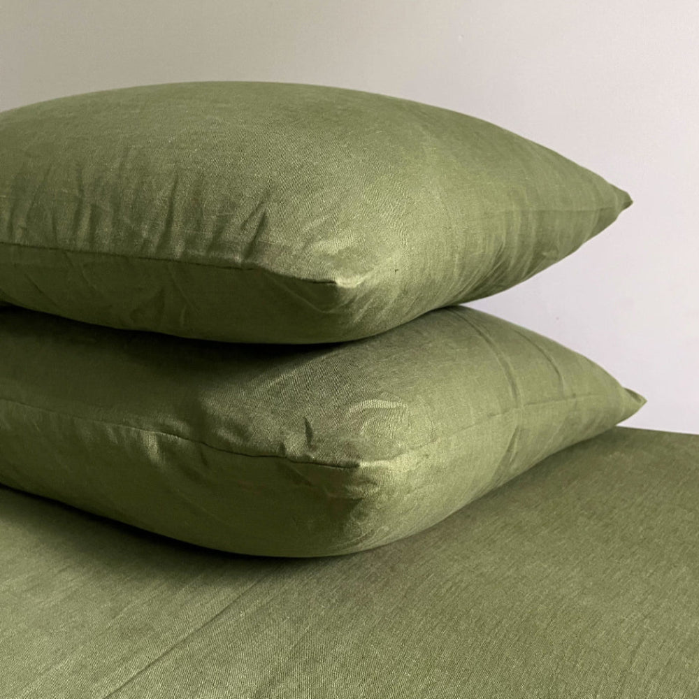 Two green pillows stacked on a matching green surface against a white background