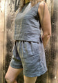 A woman wearing a sleeveless gray linen top and matching gray linen shorts